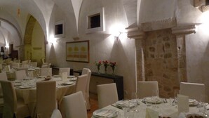 Un espace repas avec des tables dressées pour le repas, des murs blancs et des plafonds en arc de cercle.