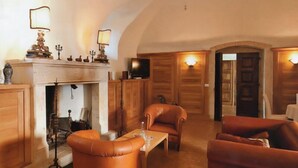 Une pièce chaleureuse avec des fauteuils en cuir, une cheminée, des meubles en bois et un téléviseur.