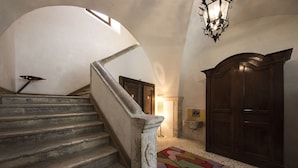 Un escalier avec une rampe en pierre, une porte en bois et un tapis à motifs sur le sol.