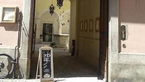L’entrée d’un immeuble, avec un balcon, une enseigne et un vélo garé à l’extérieur.