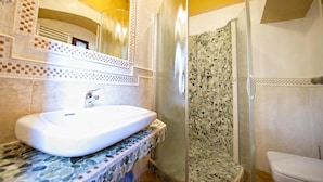Une salle de bain avec un lavabo blanc, une douche aux carreaux de mosaïque et des toilettes.
