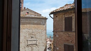 Une rue étroite bordée de bâtiments historiques, un ciel dégagé et un cadre de fenêtre.