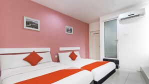 Habitación de hotel con dos camas, paredes rosas y dos cuadros enmarcados.