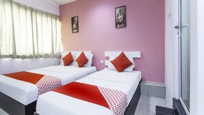 Habitación de hotel con dos camas, una pared rosa y una ventana con cortinas traslúcidas.