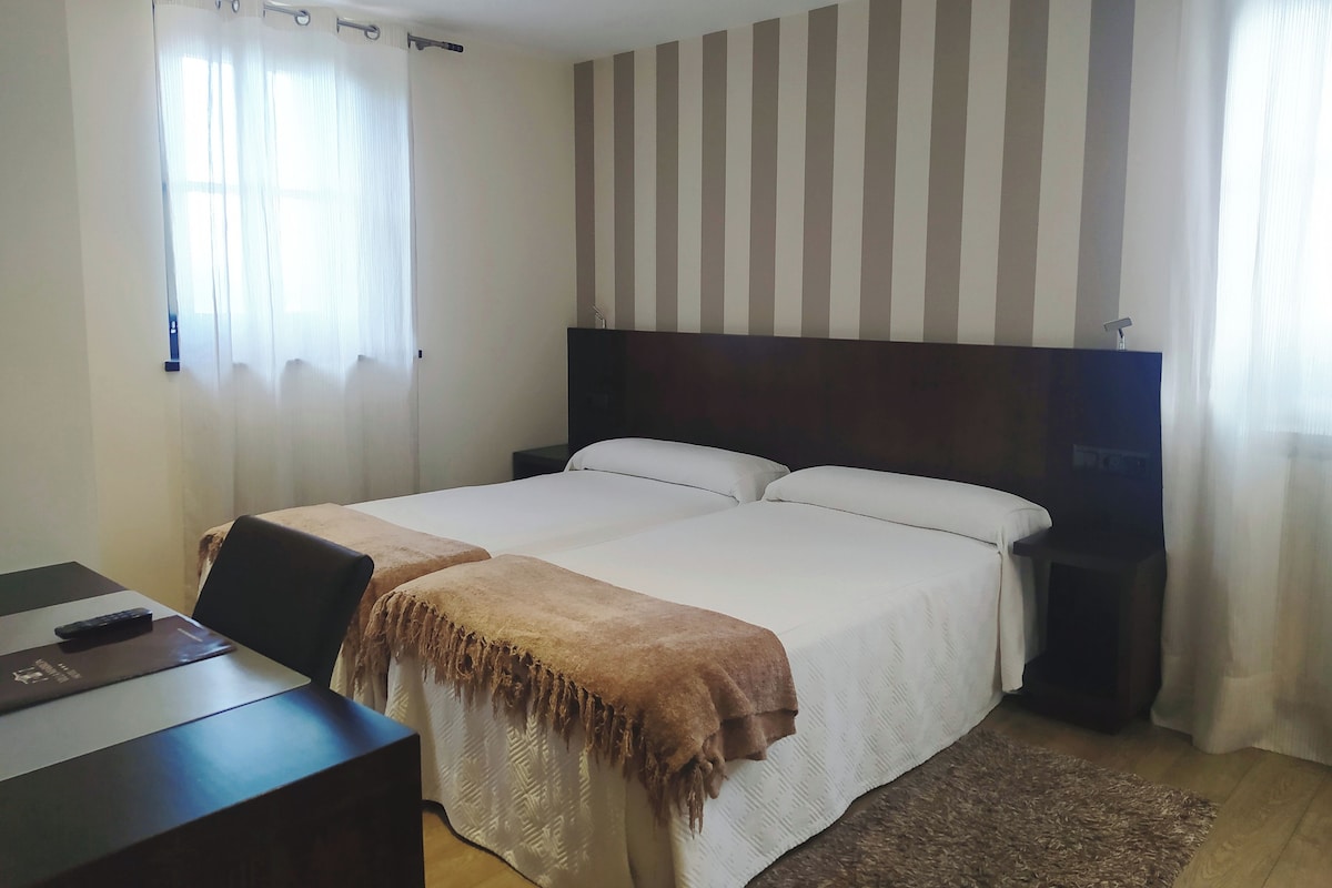 A hotel room with a large bed, a desk with a chair, and a TV on a stand.