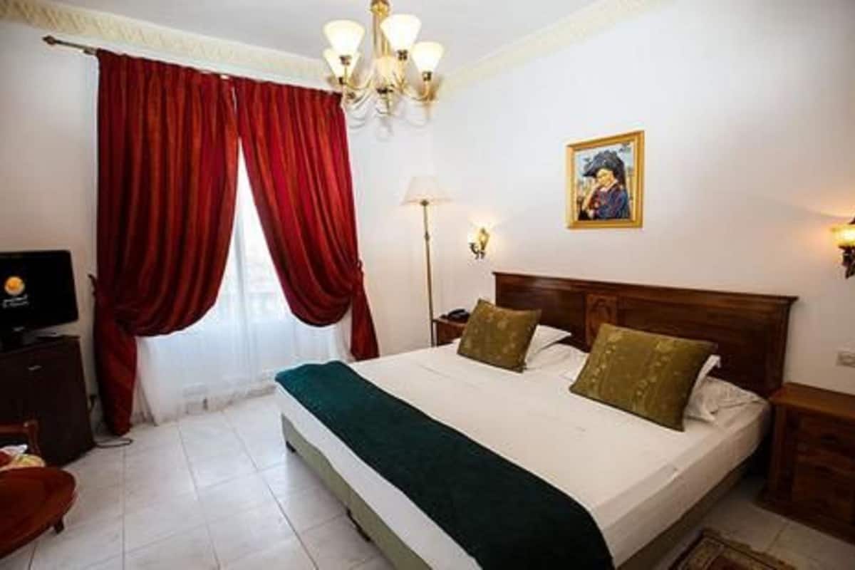 A hotel room with a bed, a television, a desk, and a chair.