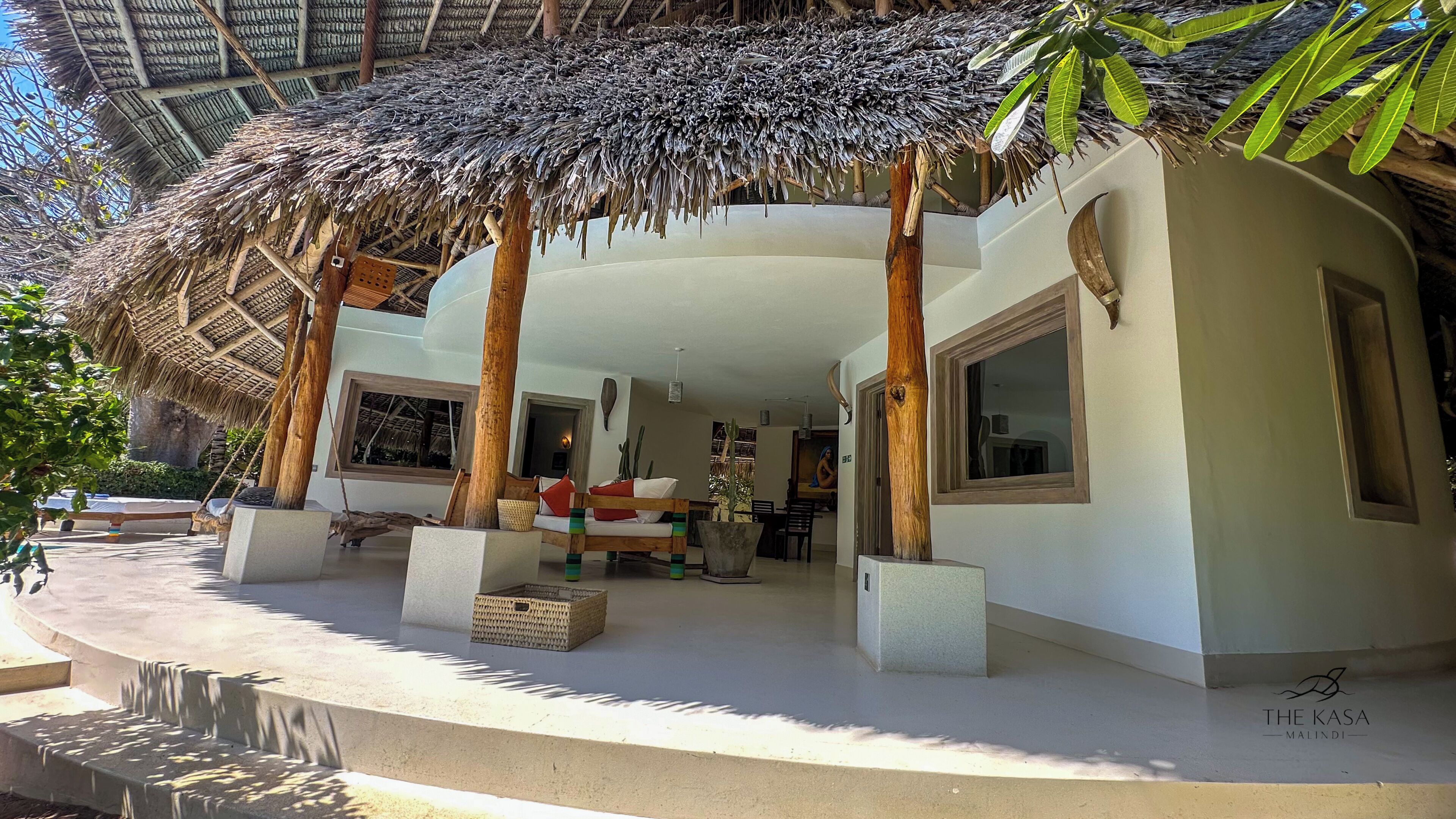A modern villa with a thatched roof, large windows, and a pool area.