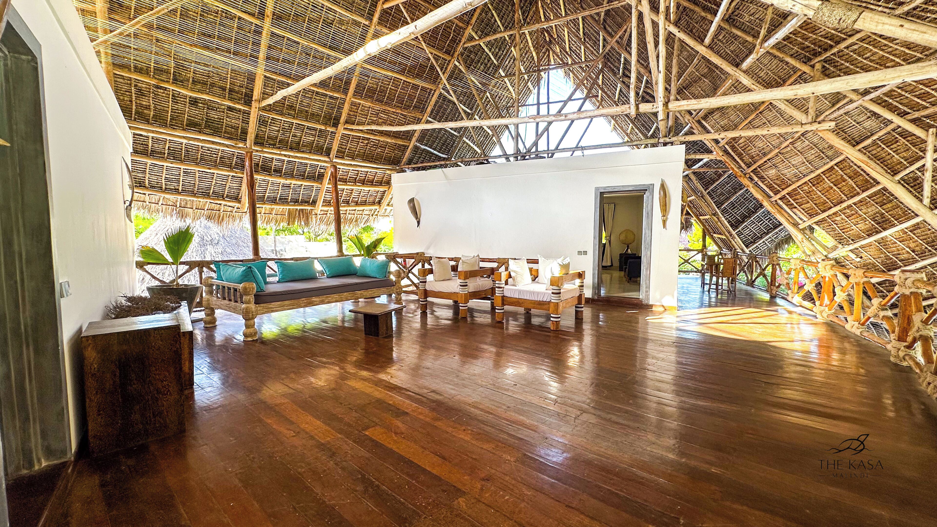 Amplia habitación con techo alto, suelo de madera y estructura de tejado de paja.