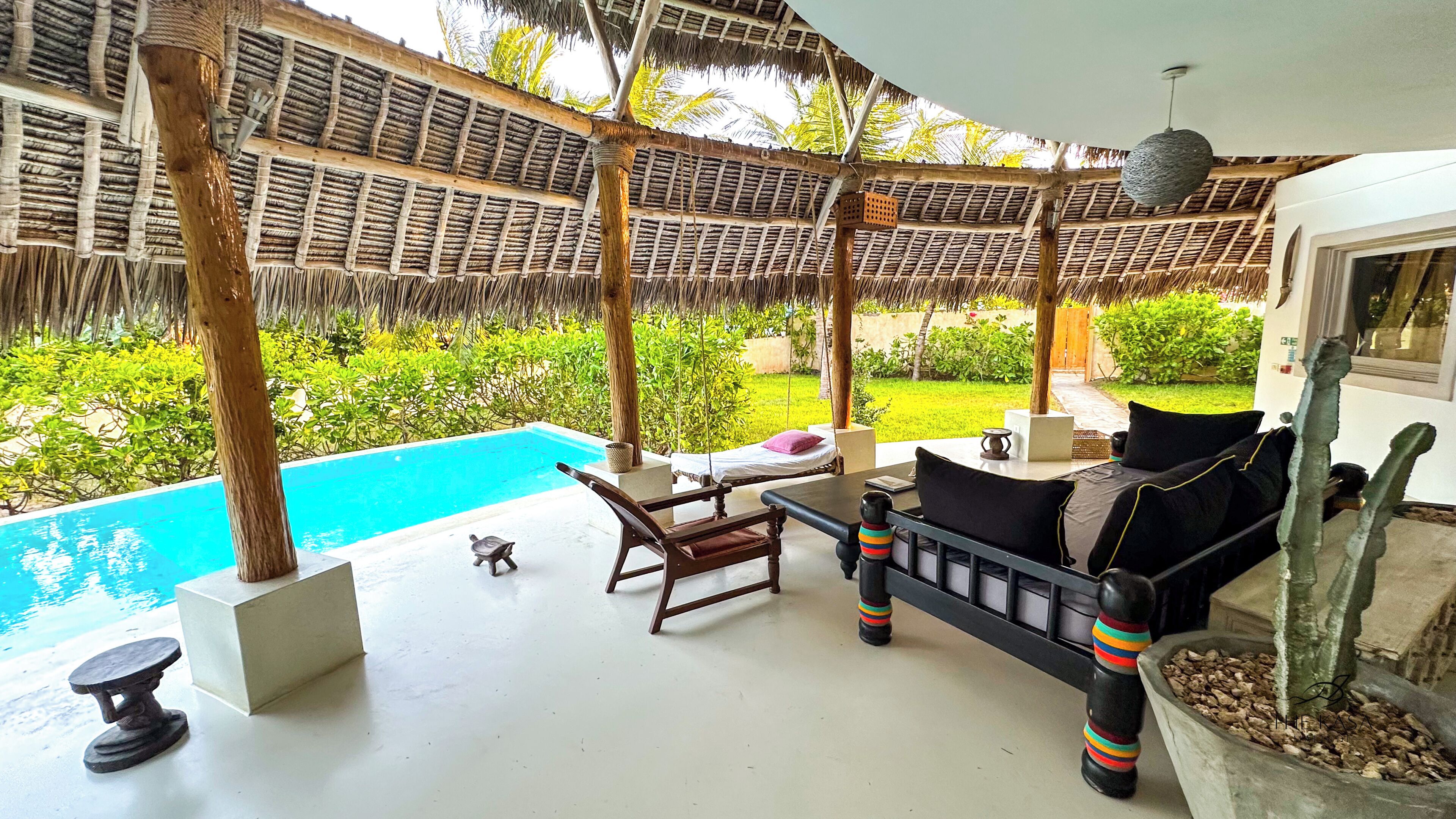 A covered outdoor area with a pool, seating, and a hanging light fixture.
