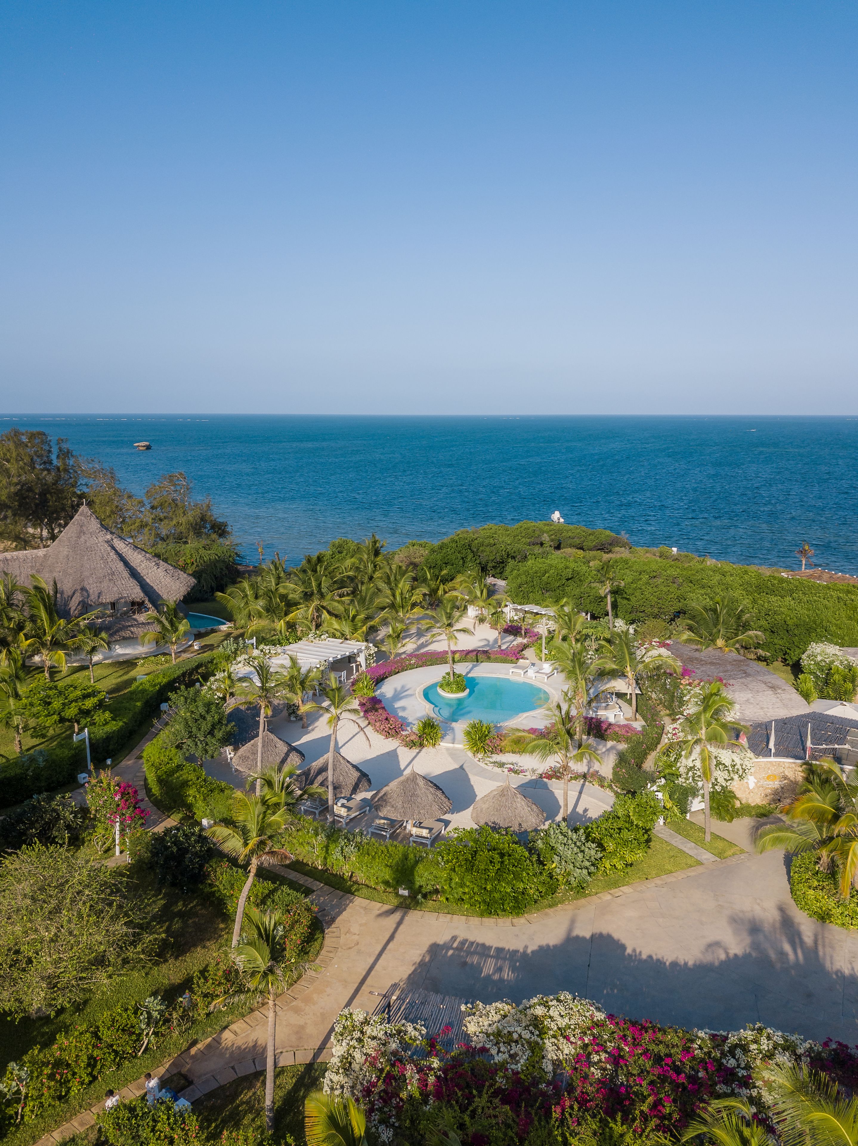Ein Resort mit einem zentralen Pool, Palmen und Blick auf den Ozean.
