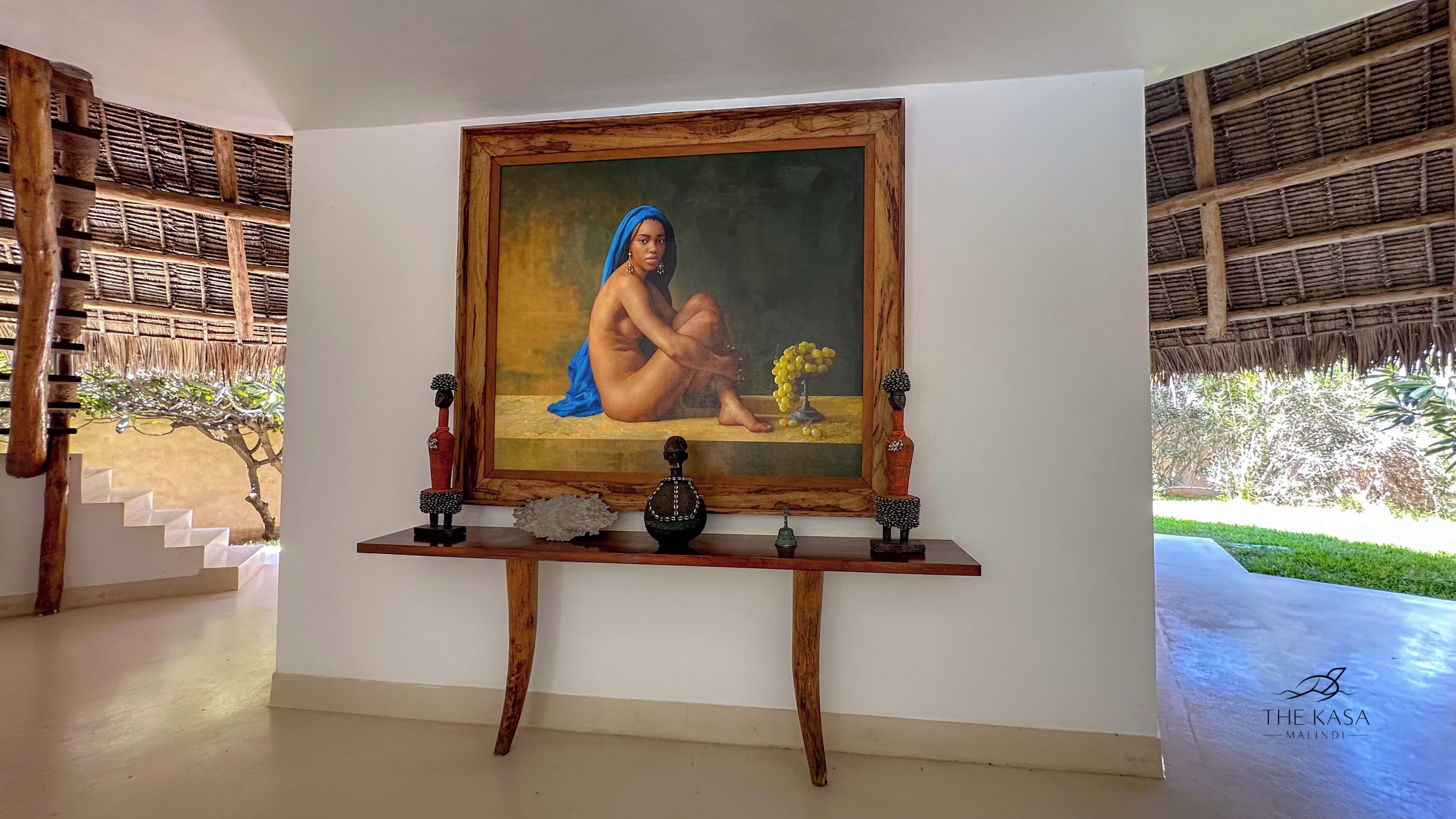 Una habitación con un cuadro, una mesa de madera y una escalera.