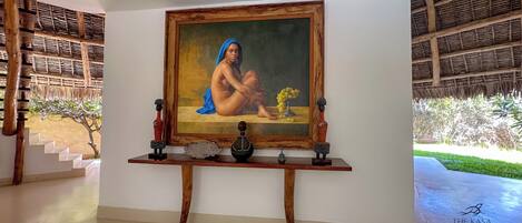 Una habitación con un cuadro, una mesa de madera y una escalera.