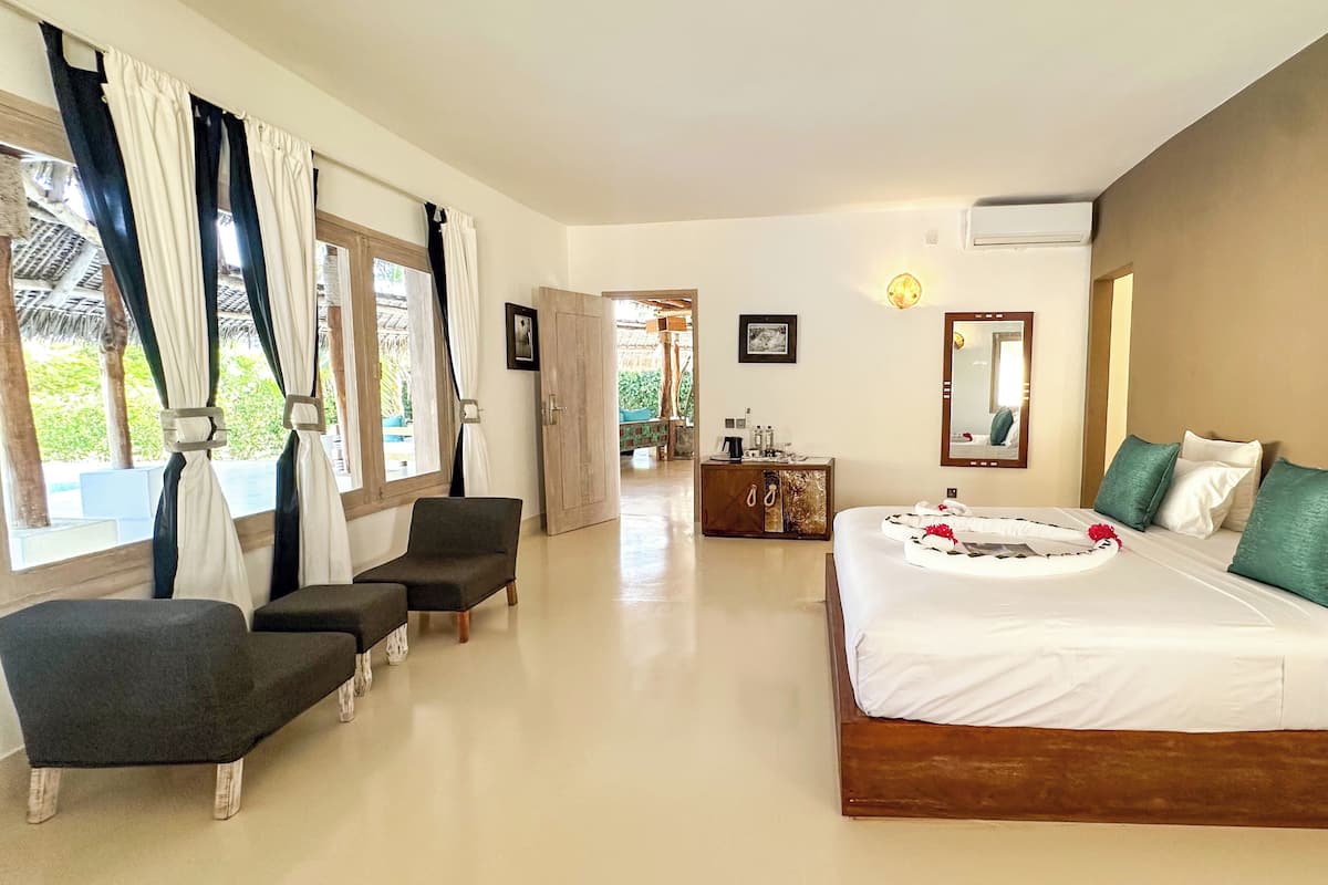 Quarto de hotel com uma cama grande, uma escrivaninha, uma cadeira e vista para o exterior.