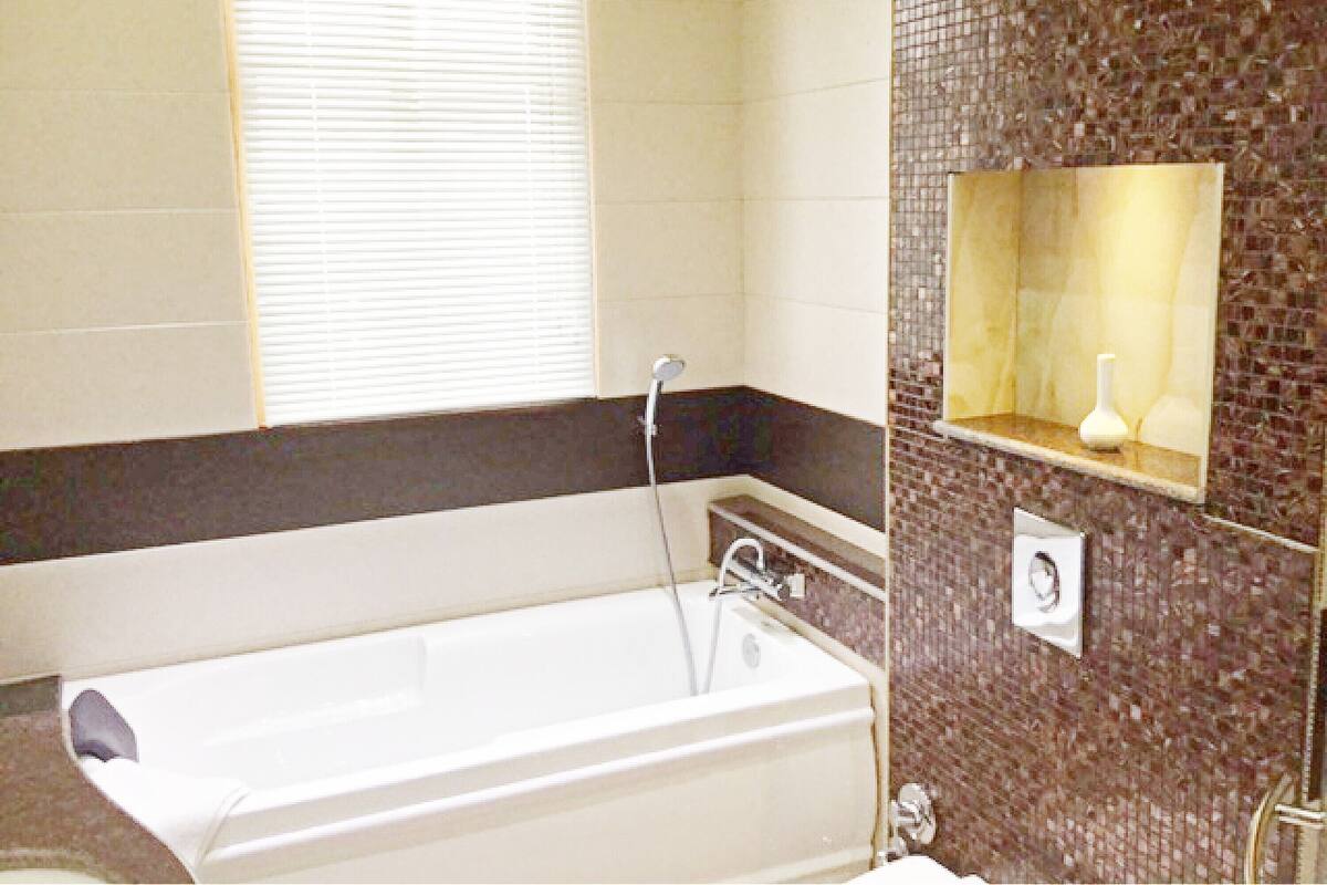 A bathroom with a bathtub, a shower, and a mirror with a vase.