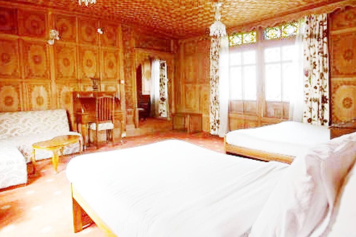 A room with two beds, a small table, a chair, and a window with curtains.