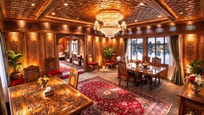 A luxurious room with ornate wood paneling, a large chandelier, and a red carpeted floor. - Mascot Houseboats (Srinagar)