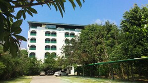 A hotel with a white facade, green shutters, and multiple balconies. - Chomdao Hotel (Rayong)