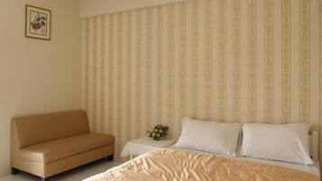 Une chambre à coucher avec un lit, un canapé et une table de chevet ornée d’un vase de fleurs.