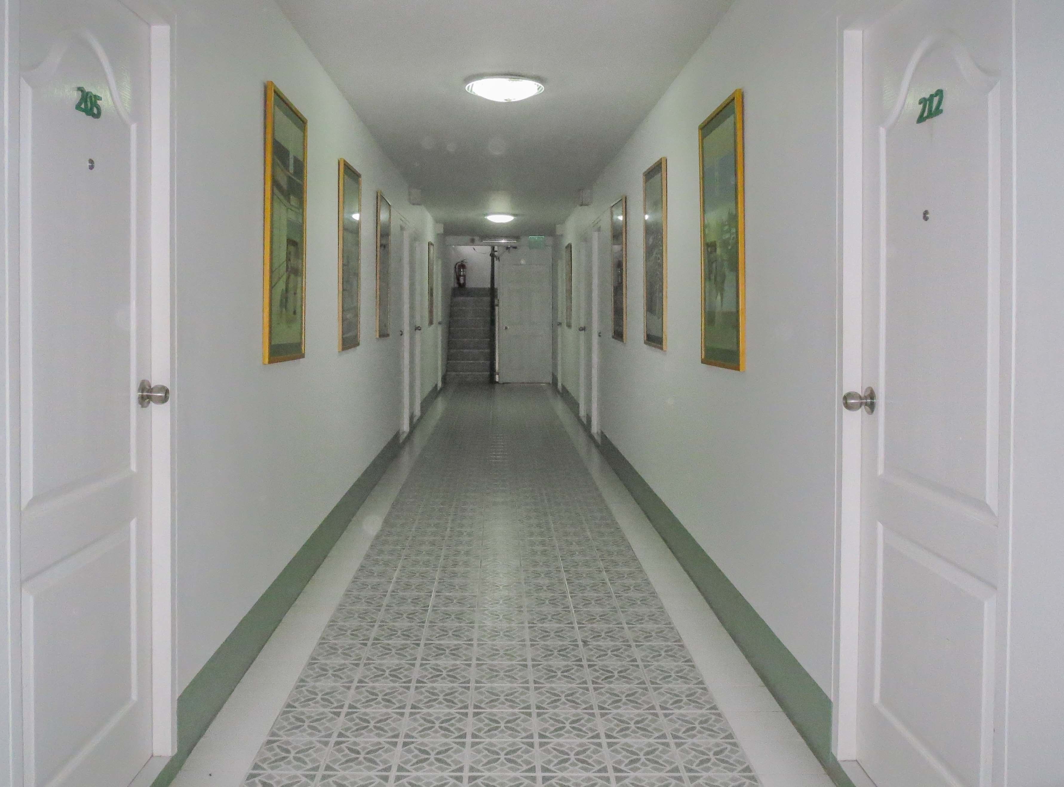 A hallway with patterned floor tiles, white doors, and framed pictures on the walls.