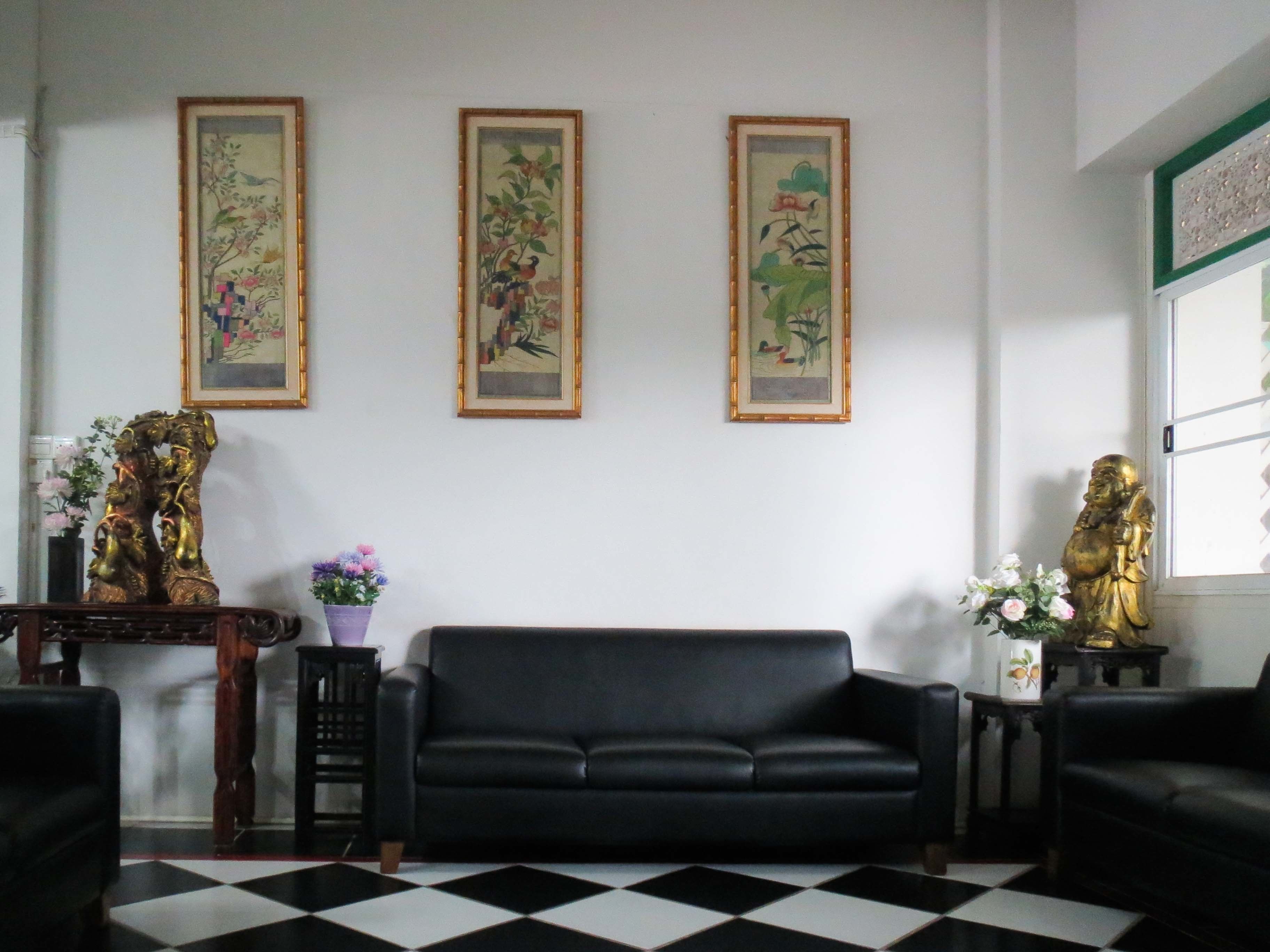 A living room with a black sofa, a checkered floor, and three framed paintings on the wall.