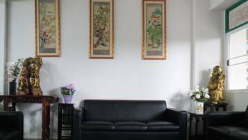 A living room with a black sofa, a checkered floor, and three framed paintings on the wall.