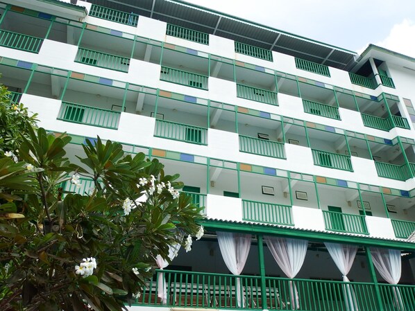 Un hotel de varios pisos con balcones, barandal verde y fachada blanca.