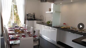 Una cocina moderna con armarios blancos, una mesa de comedor con platos y vasos, y vistas al exterior a través de una ventana.