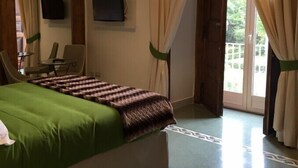 Habitación de hotel con cama, televisión, escritorio y vistas al exterior.