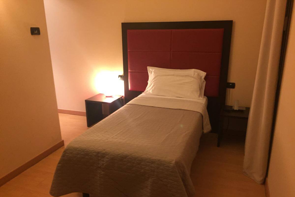 Una cama individual con cabecera roja en una habitación de hotel.