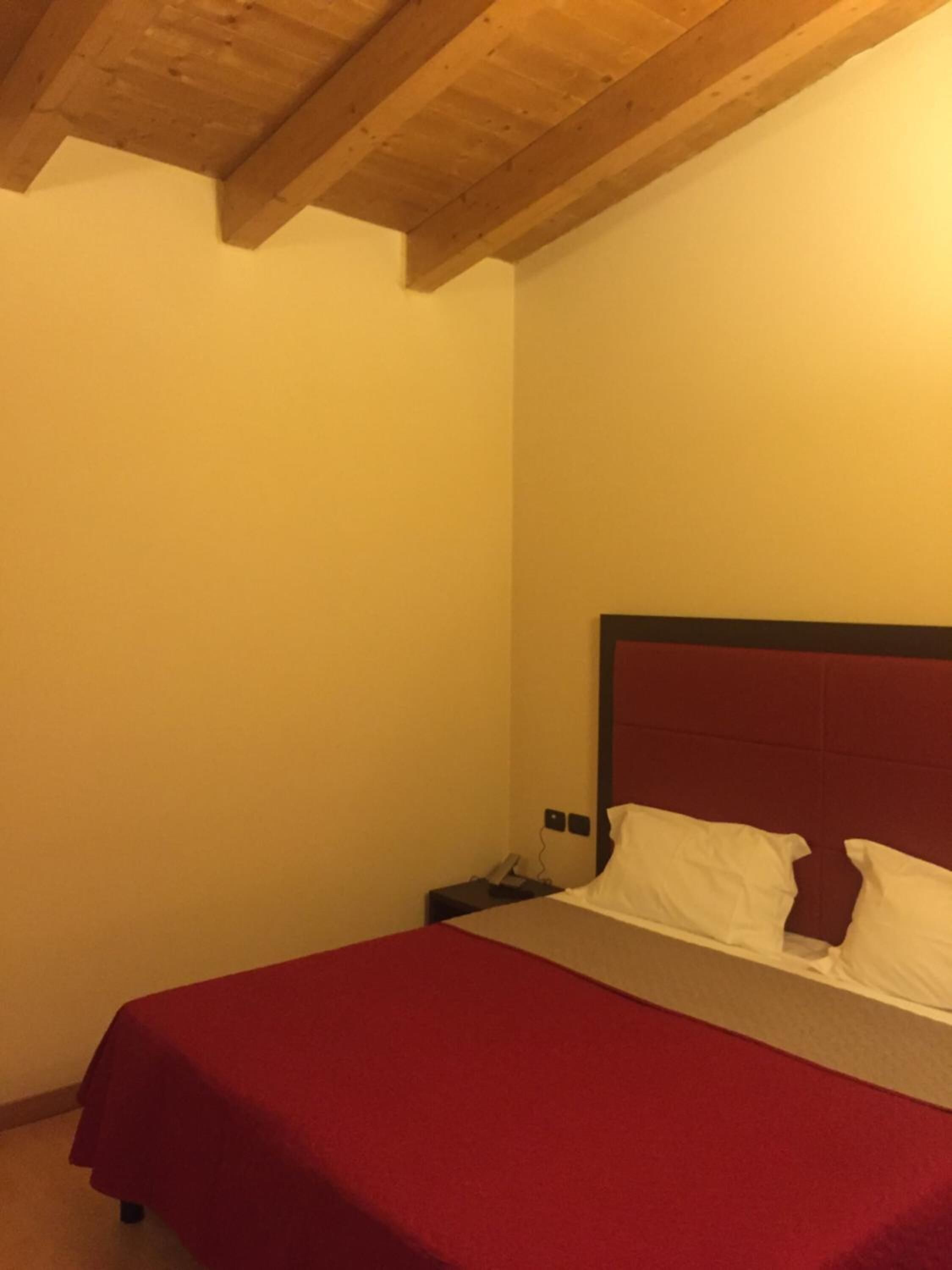 Un dormitorio con una cama individual, una mesita de noche y techo de madera.
