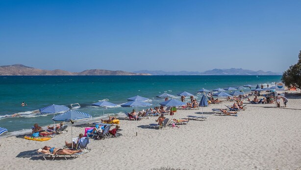 A beach with rows of blue and white striped umbrellas and lounge chairs. - Cavo D'oro Hotel (Kos)