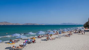 Aan het strand, ligstoelen aan het strand, parasols, een strandbar