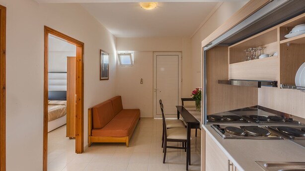A compact kitchen with a dining area, a sofa, and a small table. - Cavo D'oro Hotel (Kos)