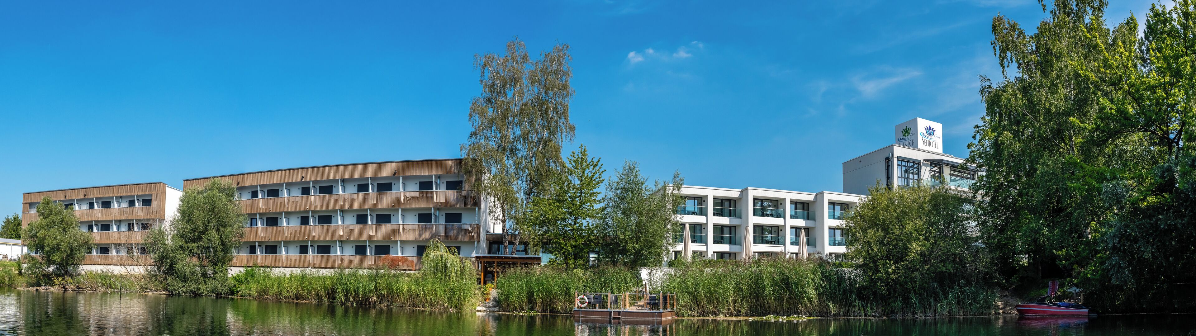 Een modern hotel met meerdere verdiepingen, een steiger en een rivier.