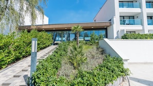 A modern building with a glass facade, surrounded by lush greenery and a clear blue sky. - Seehotel Forst (Forst)