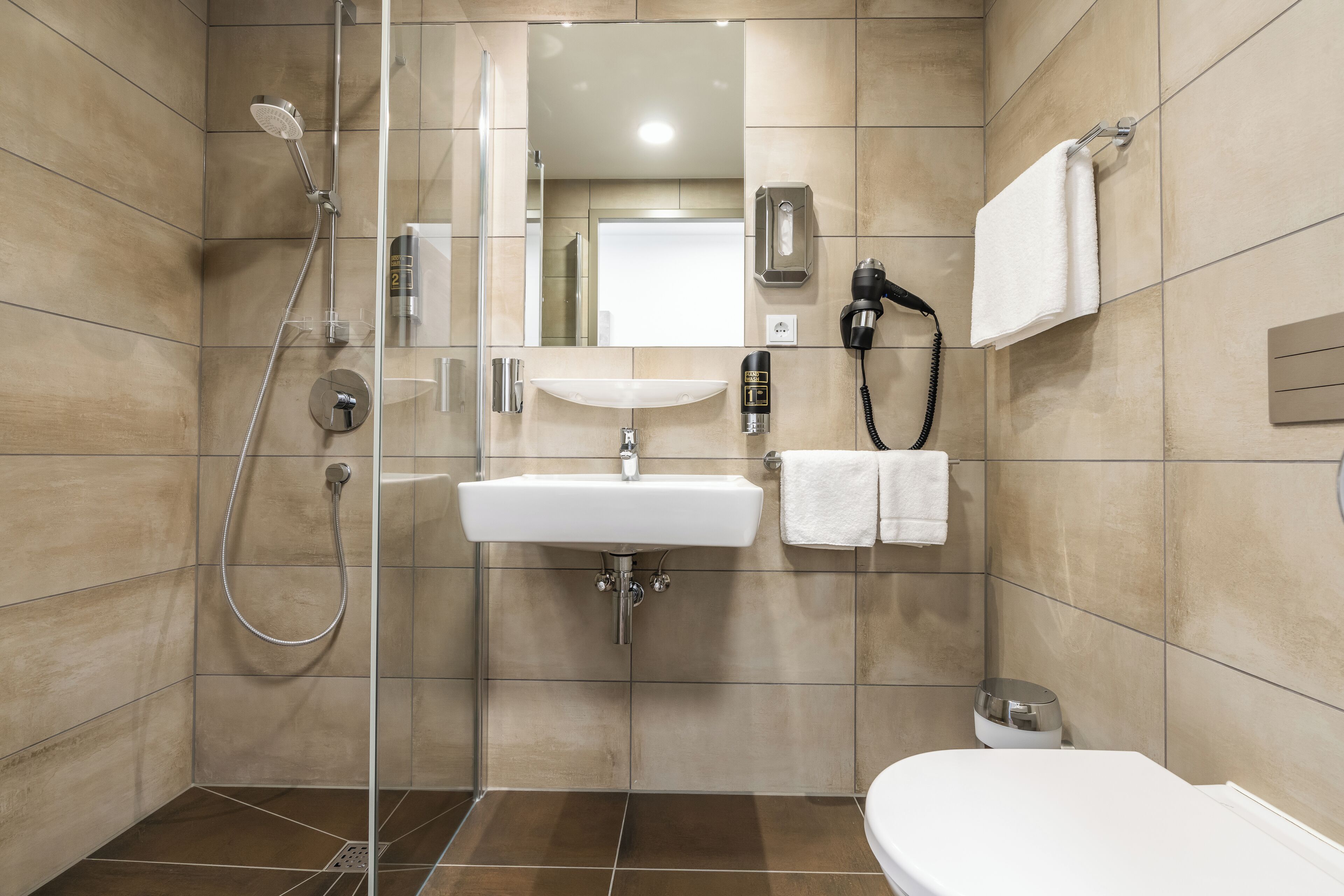 A modern bathroom with a glass-enclosed shower, a white sink, and a toilet.