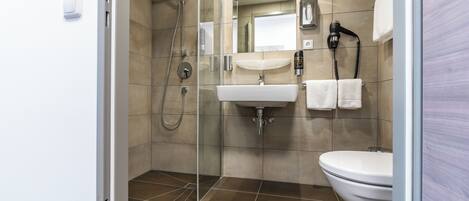 A modern bathroom with a glass-enclosed shower, a sink, and a toilet.