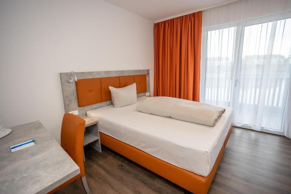 A hotel room with a bed, a desk, and a chair.