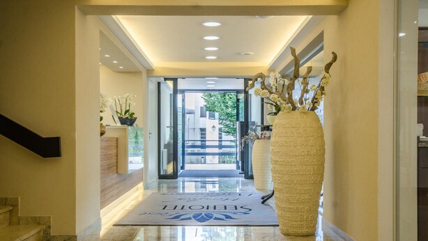 A hotel lobby with a marble floor, a reception desk, a large vase with flowers, and a welcome mat. - Seehotel Forst (Forst)