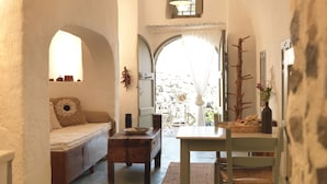 Una habitación acogedora con un sofá, una mesita y una mesa de comedor. Hay una ventana con cortinas y vistas al exterior.