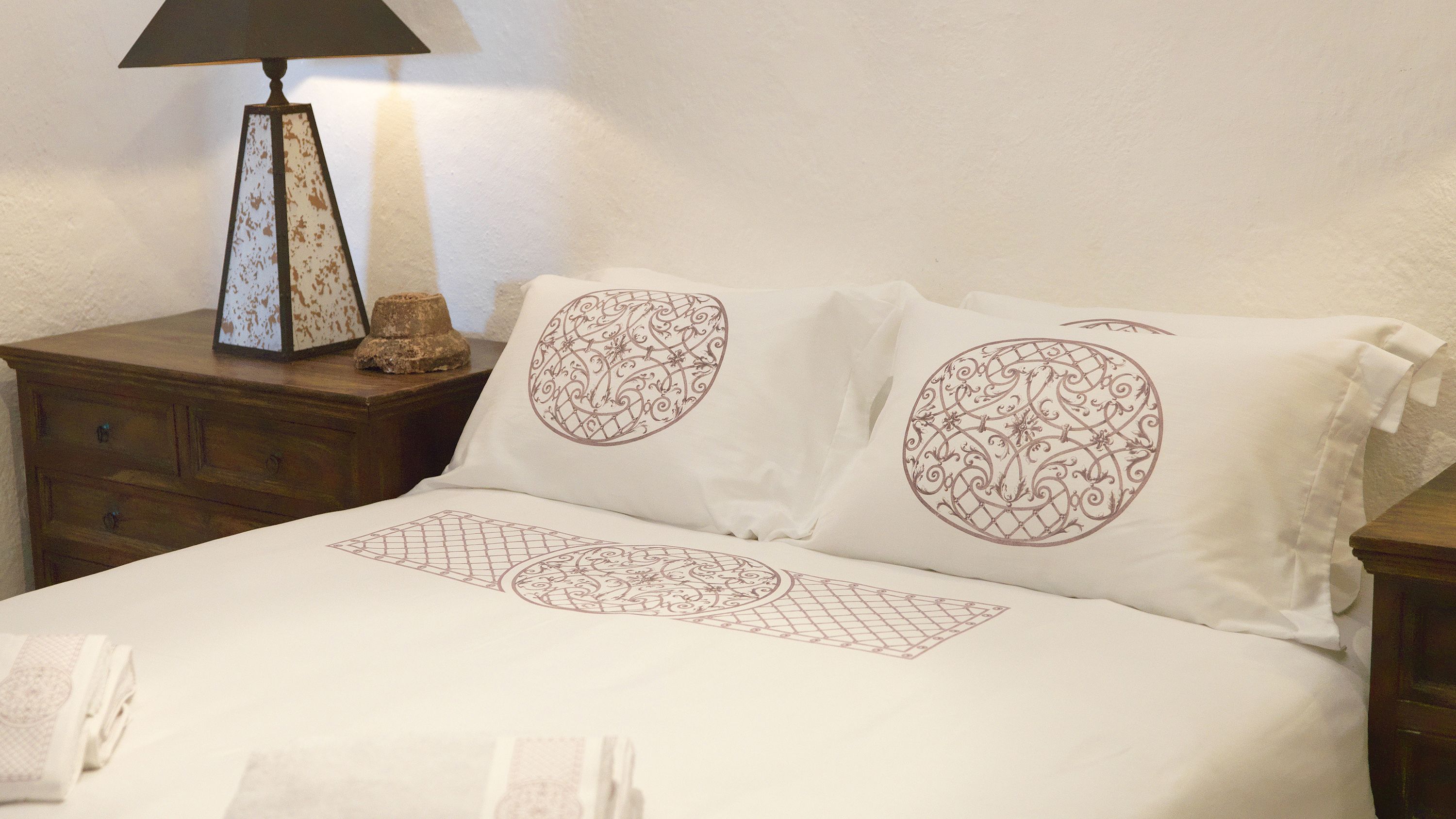 A neatly made bed with decorative pillows and a bedside table with a lamp.
