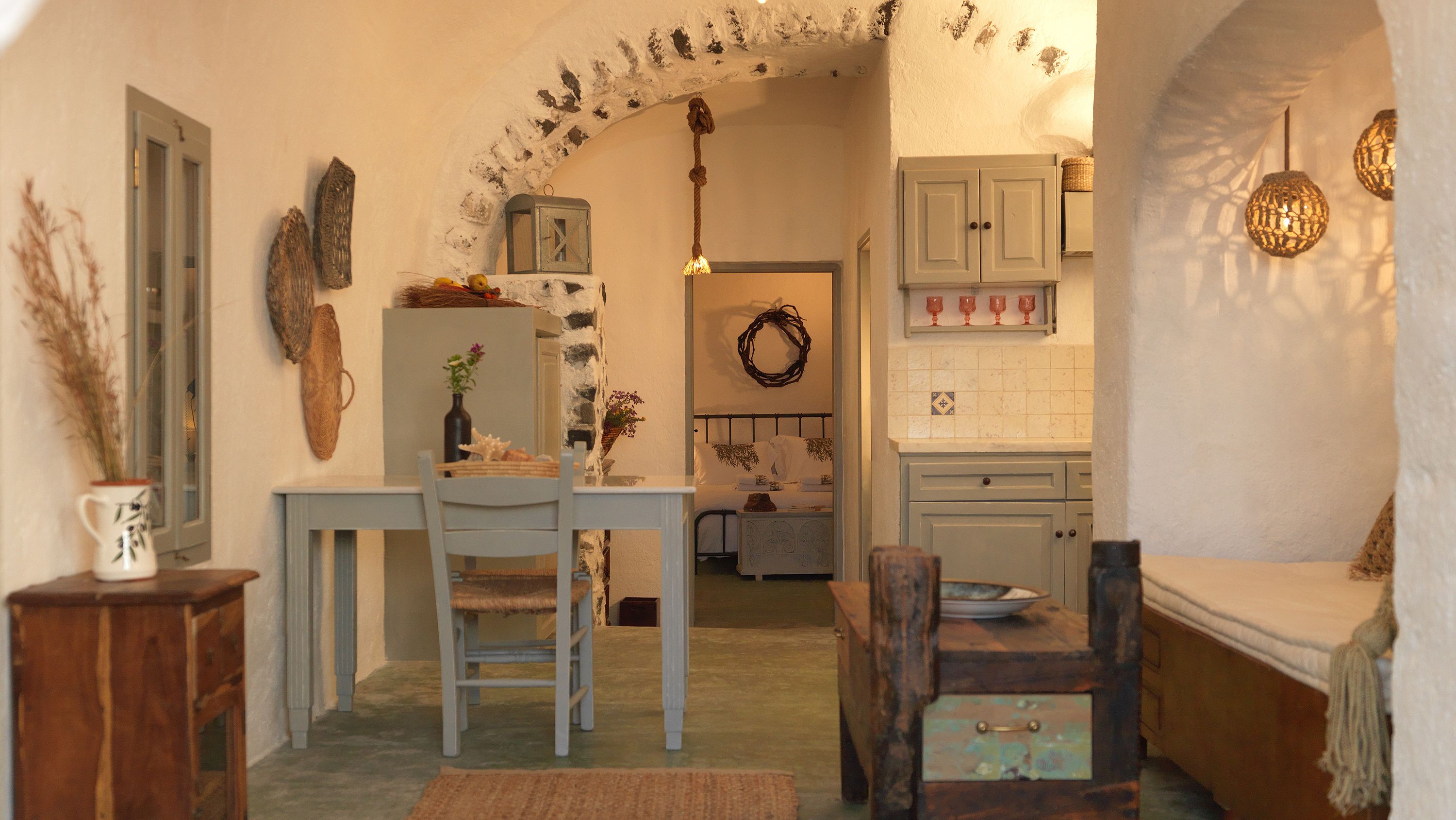 A cozy, rustic interior with a dining area, kitchen, and a hallway leading to a bedroom.
