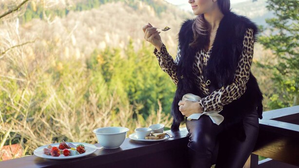 Una persona sentada a una mesa con comida, con vistas a un paisaje montañoso.