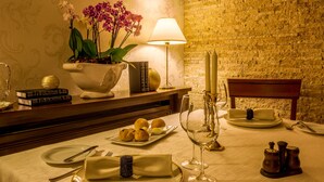 Una mesa de comedor preparada con platos, cubiertos, una copa de vino y una vela.