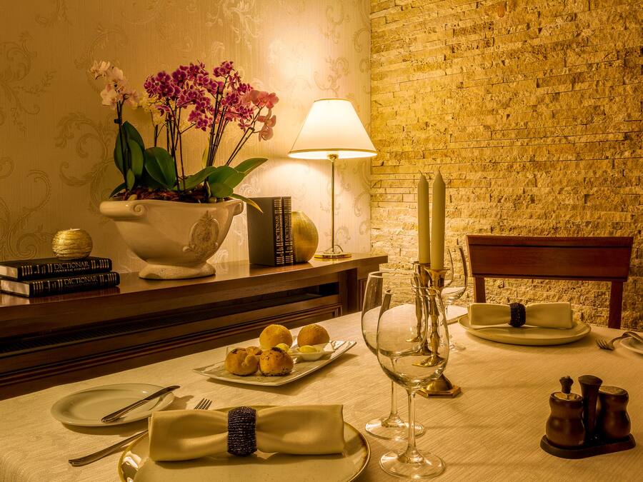 Una mesa de comedor preparada con platos, cubiertos, una copa de vino y una vela.