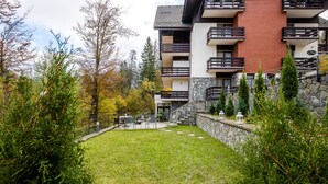 Un patio con césped, pared de piedra y un edificio con balcones y un letrero que dice 'Hotel'.