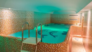 Una piscina con mosaicos y una escalera de metal.