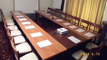 A conference room with a long table, chairs, a projector, and a whiteboard.