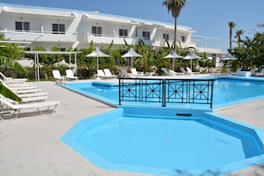 Relax by the pool surrounded by lush greenery and comfortable lounge chairs.