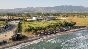 Un hôtel situé sur la côte, avec vue sur la plage, un parking et une pelouse aménagée.